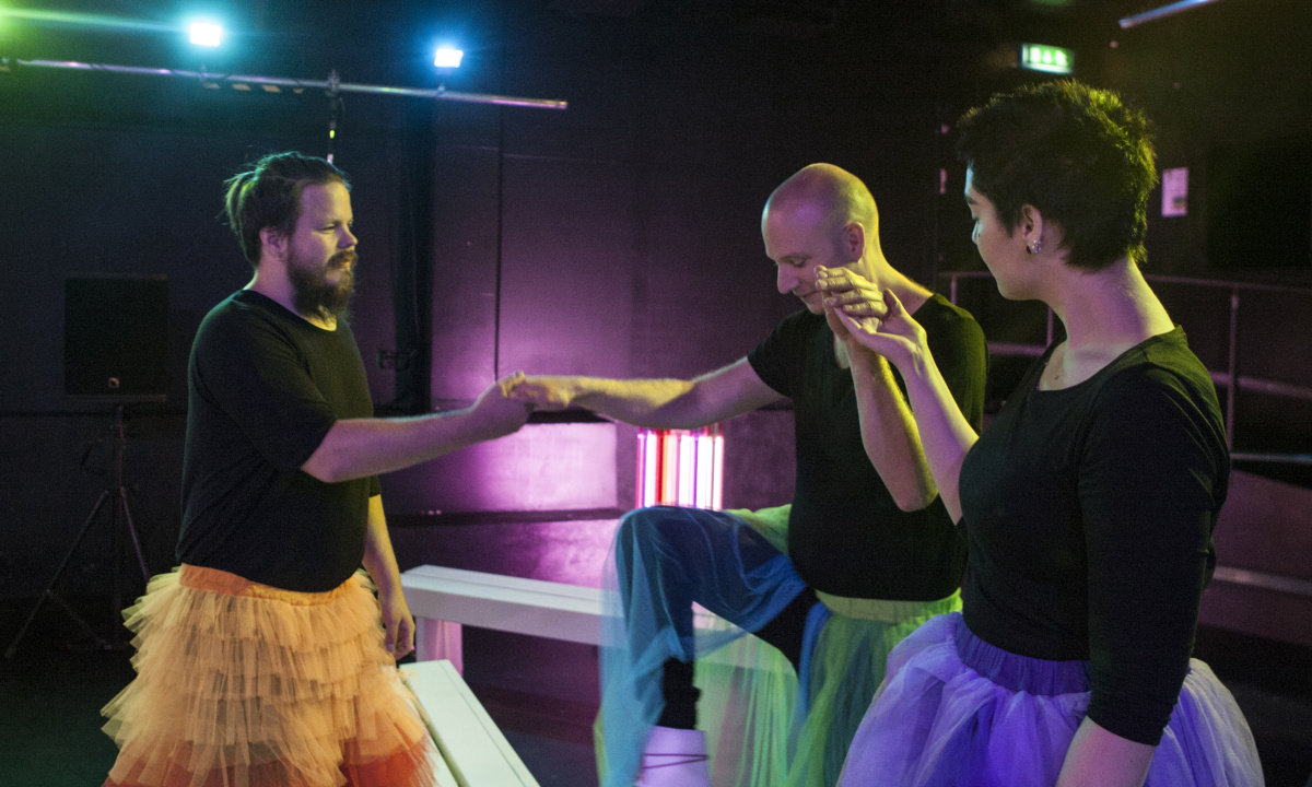 tre personer i ballerinakjol håller hand